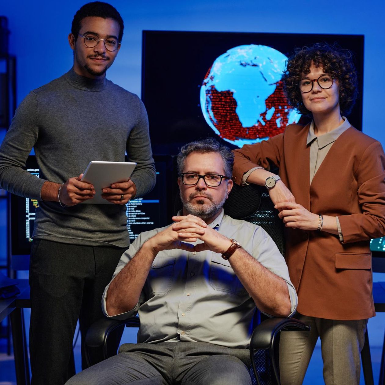 2 men and 1 woman tech founders smiling and posing in front of computer screens with code